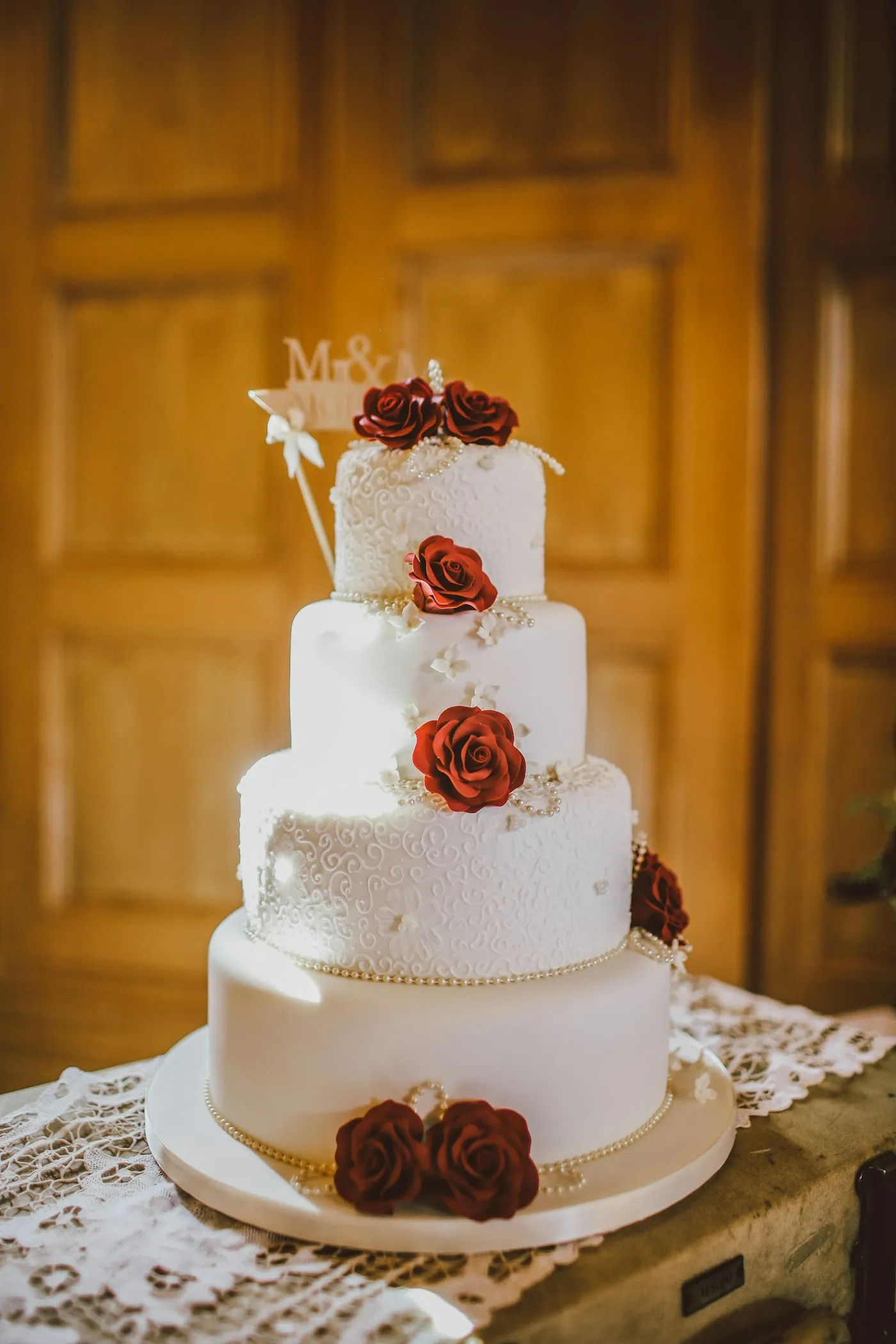 Four-tier ivory wedding cake dressed with pale sugar flowers.