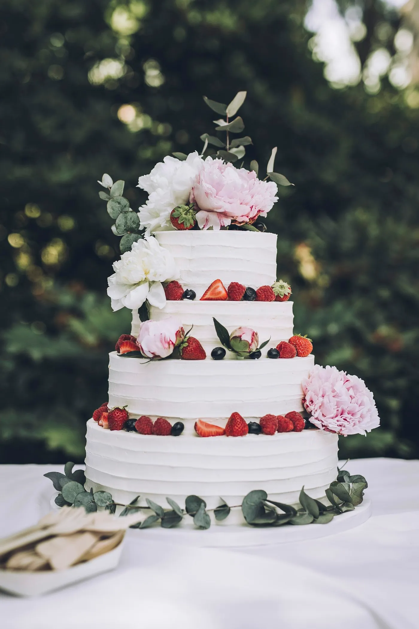 White wedding cake decorated with fresh strawberries and flowers.